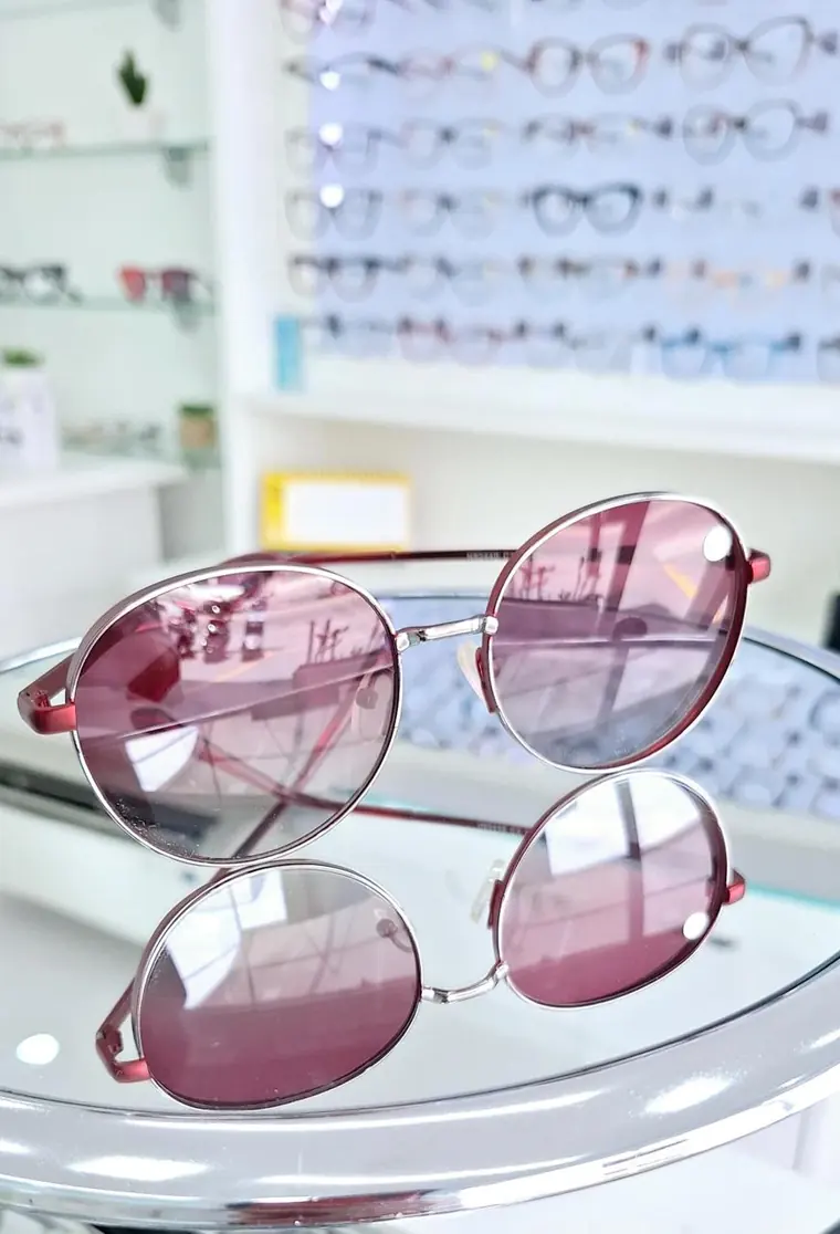 Óculos de sol de lentes rosa em expositor de vidro