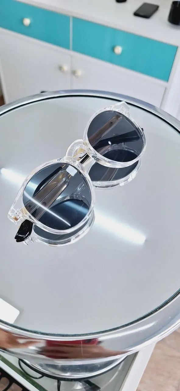 Óculos redondos de lentes transparentes sobre expositor espelhado